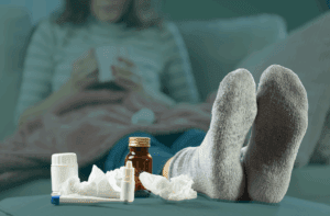 Sick woman with medication and tissues on a table