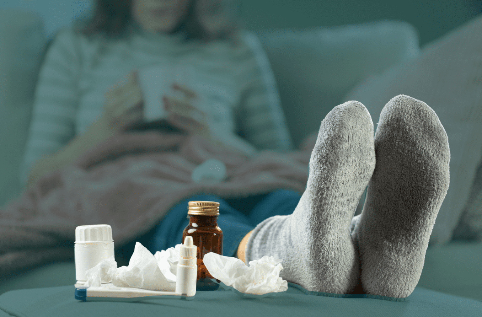 Sick woman with medication and tissues on a table